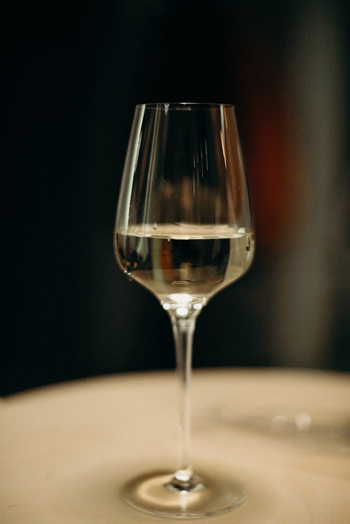 Close-up of a glass of white wine on a table with a warm background.